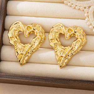Detailed view of golden heart studs with lava texture in a beige velvet jewelry box