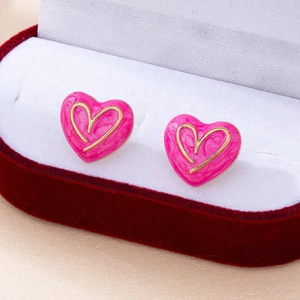 Detailansicht eleganter rosa Herz-Ohrstecker mit Goldrand in einer roten Samtbox