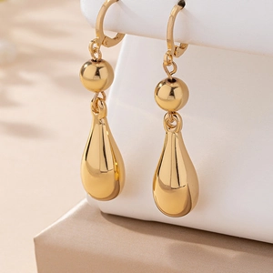 Elegant gold teardrop earrings with a polished finish on a luxury display stand