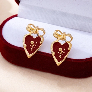Gros plan de boucles d'oreilles cœur vintage en émail rouge et rose dorée en boîte