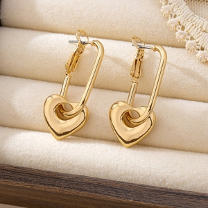 Orecchini a cuore dorati con chiusura rettangolare su sfondo in velluto beige