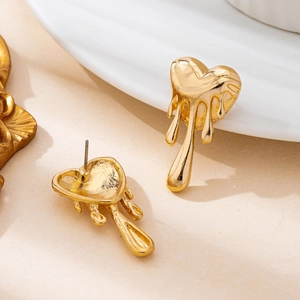 Chic golden liquid heart earrings with molten lava design on marble background