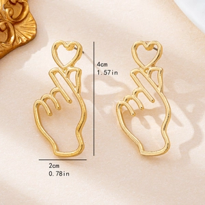 Boucles d'oreilles minimalistes dorées en forme de main cœur sur fond beige