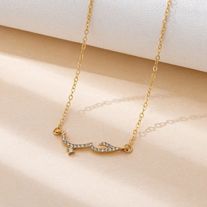 Macro detail of gold-plated necklace featuring Arabic calligraphy pendant with white crystals
