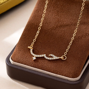 Elegant gold Arabic 'Hub' calligraphy necklace with pave crystals on brown display