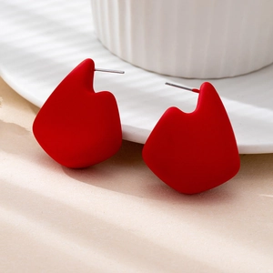 Macro shot of matte red geometric abstract stud earrings featuring unique artistic shapes
