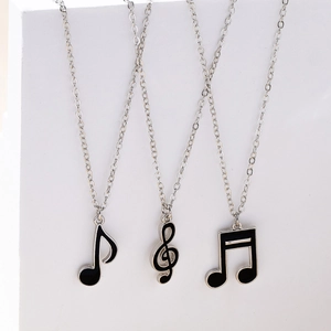 Vue détaillée de trois colliers pendentifs notes de musique sur un support géométrique