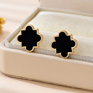Minimalist black geometric stud earrings with gold trim in a beige luxury jewelry box