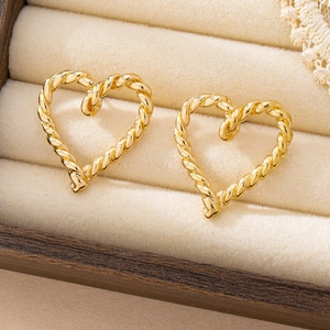 Minimalistische goldene Herzohrstecker mit Kordelstruktur auf beige Samt