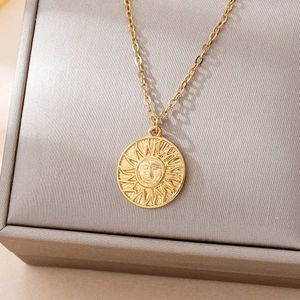 Collier pendentif soleil vintage au fini doré présenté dans un coffret à bijoux de luxe