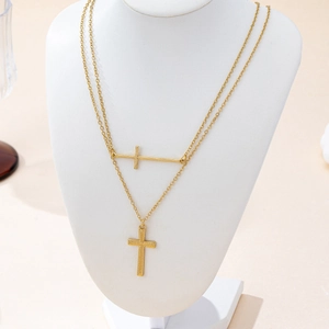 Minimalist double cross pendant necklace in gold finish on white mannequin bust