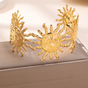 Golden bohemian style open cuff bracelet featuring hammered sun motif design charms