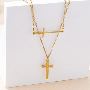 Detailed view of golden double cross pendant necklace with textured granular finish