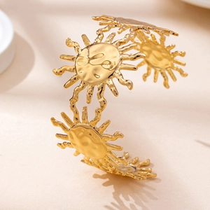 Macro shot of gold sun motif open cuff bracelet with hammered texture and bohemian style