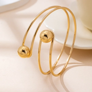 Detailed close-up of a double-layer golden spiral open bangle with polished ball ends