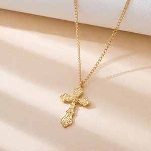 Detailed macro view of golden gothic cross pendant with baroque floral texture engravings