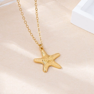 Elegant gold starfish pendant necklace with spiral design on a minimalist textured surface