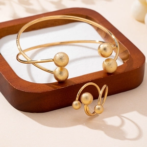 Set minimalista bracciale e anello dorati con perle satinate su vassoio in legno