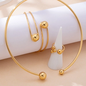 Minimalist gold jewelry set with torque necklace, wrap bracelet and beaded ring on display