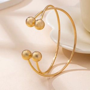 Detail of minimalist gold double-line open bangle featuring four frosted metallic beads