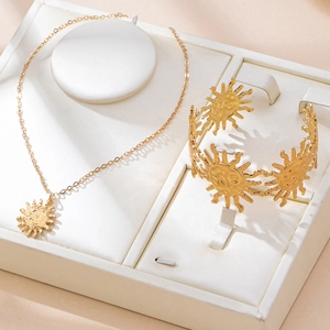 Golden jewelry set with sun pendant necklace and hammered cuff bracelet on white tray