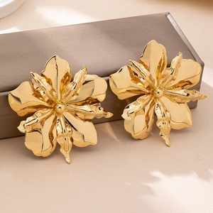 Exaggerated gold irregular flower stud earrings displayed on a luxury jewelry box