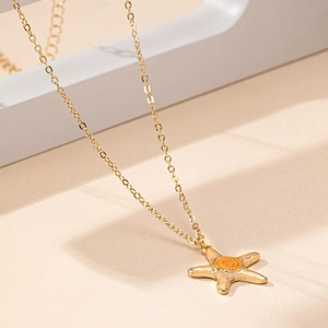 Detailed macro view of a gold starfish pendant necklace with an orange spiral center