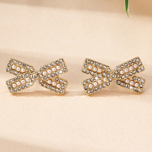 Détail de boucles d'oreilles nœuds dorées avec cristaux étincelants et perles