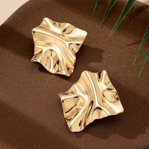 Modern gold geometric stud earrings with irregular pleated texture on dark surface