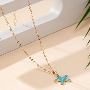 Collier en or à la mode avec pendentif étoile de mer bleu clair sur fond de sable