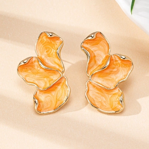 Gros plan de boucles d'oreilles fleurs en émail orange irrégulier aux bords dorés
