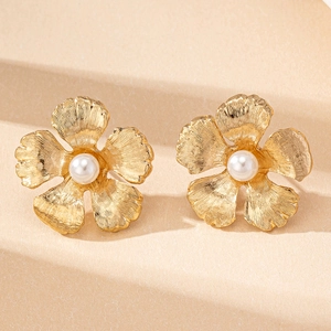 Macro de boucles d'oreilles fleurs dorées avec pétales brossés et perle blanche centrale