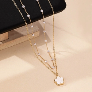 Elegante goldene Doppelschicht-Halskette mit weißen Perlen und minimalistischem Blumenanhänger