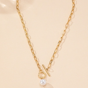 Dettaglio della collana a catena dorata con chiusura a T e ciondolo di perla bianca