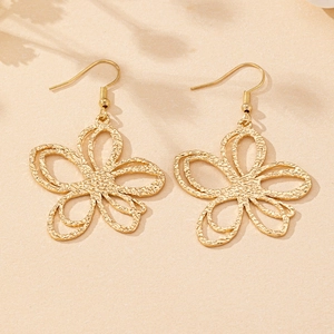 Detailed close-up of gold hollow flower earrings with hammered texture and double layers