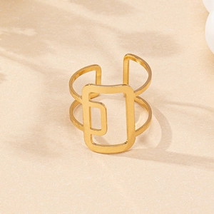 Macro detail of golden geometric hollow square ring on a warm textured sandy surface