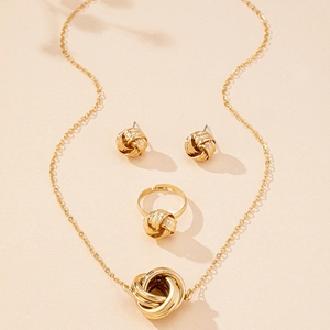 Dettaglio del set di gioielli con nodo intrecciato dorato con collana, orecchini e anello