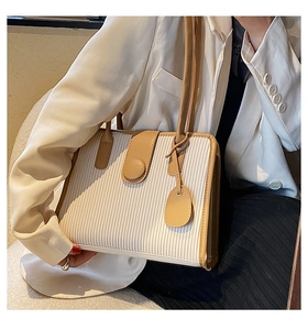 Detail view of structured handbag featuring vertical pleated texture and contrast trim