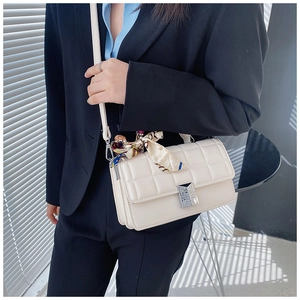 White quilted crossbody bag with silver buckle and decorative scarf on the handle