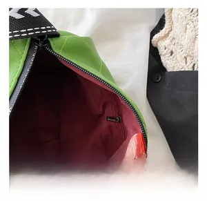 Macro shot of green quilted PU leather bag interior with burgundy lining and zip pocket