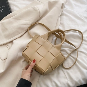 Elegant khaki woven crossbody bag with dual handles on a beige blazer setting