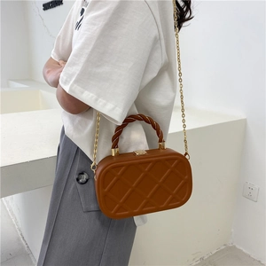 Brown quilted crossbody bag with twisted top handle and gold chain strap in studio