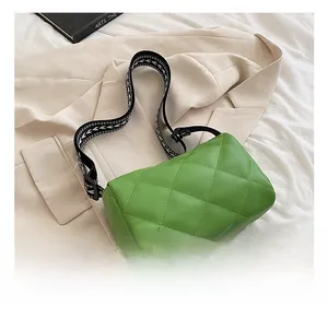 Close-up of green quilted PU leather bag featuring a black and white geometric woven strap