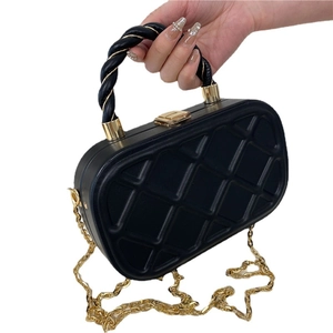 Quilted black chain crossbody bag with gold hardware and twisted handle on white background