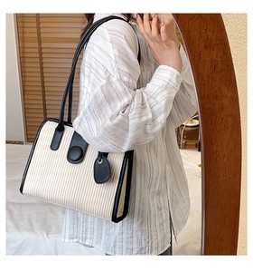 Detail of off-white pleated tote bag featuring black leather trim and contrast handles