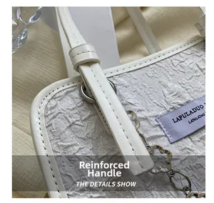 Détail du sac cabas blanc montrant les poignées renforcées et les boucles en métal