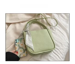 Detail of light green leather bucket bag featuring a decorative floral silk scarf handle