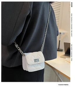 Detailed view of mini white quilted crossbody bag with silver chain on model in office