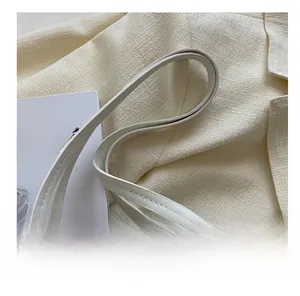 Détail du sac cabas en cuir blanc avec texture gaufrée et boucles en métal argenté