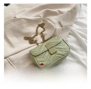 Detail of sage green quilted mini bag with gold chain strap and metallic lock closure
